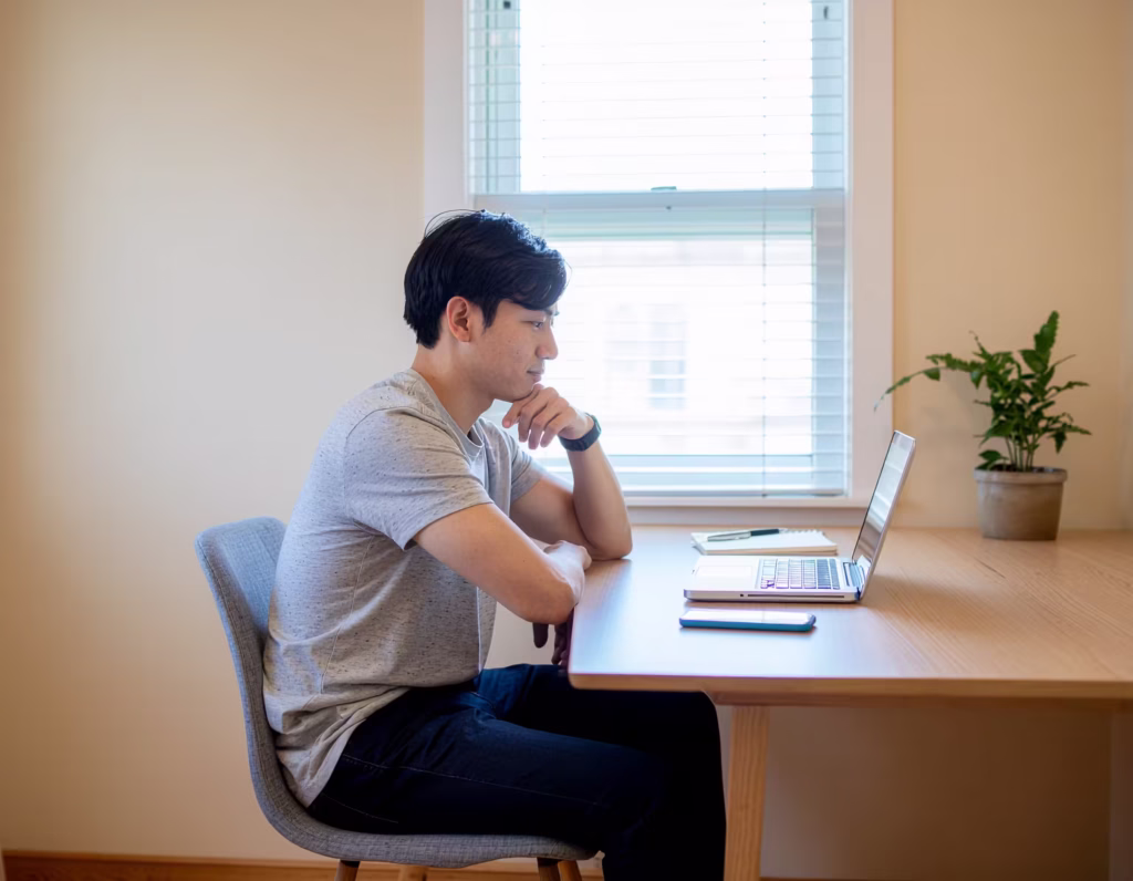 Job seeker carefully reviewing a remote job offer email on a laptop at home
